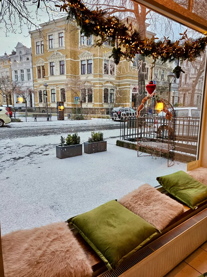 A cosy window seat with green cushions and a view of snow-covered Bonn’s Südstadt