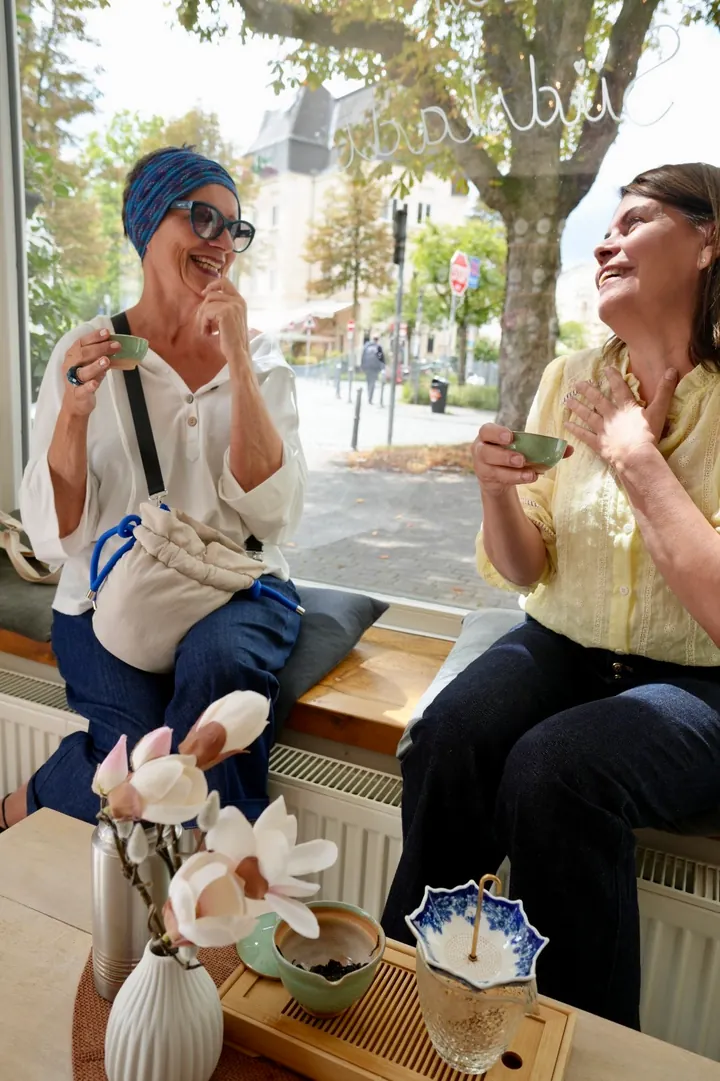 Maria and a guest enjoying tea together by the tea room window