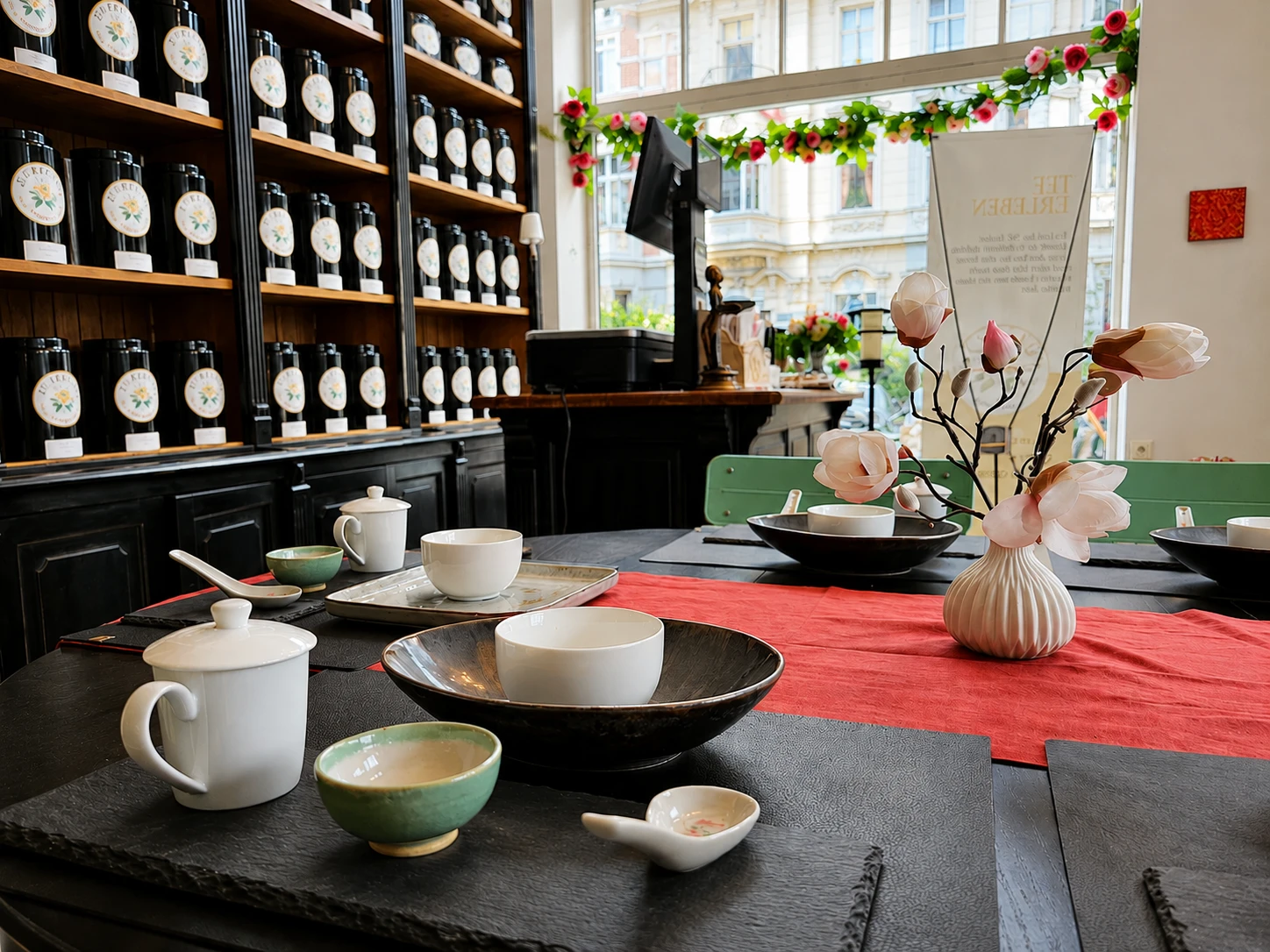 Gedeckter Tea-Time-Tisch im Lupercia Salon vor der Wand mit schwarzen Teedosen