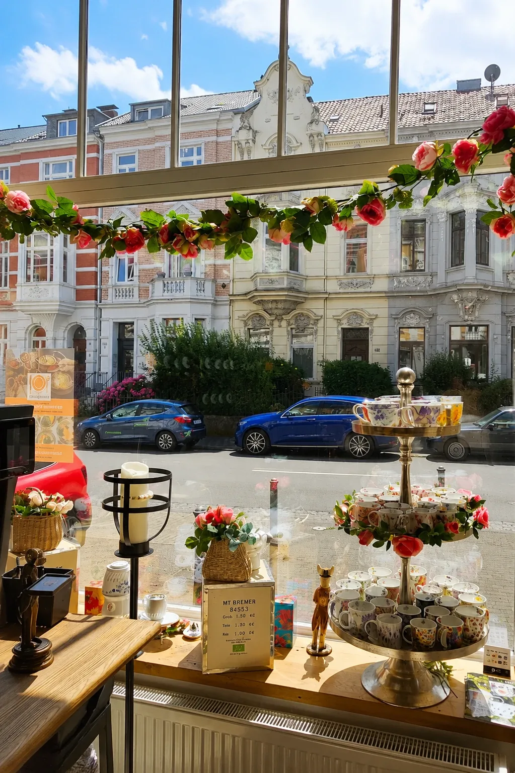 Floral teacups and a rose garland in Lupercia’s shop window, with the historic houses of Bonn’s Südstadt behind