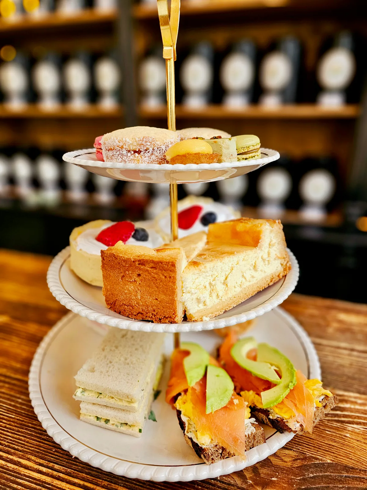 Una bandeja de tres pisos para la merienda con repostería fina, tartas, sándwiches y tostas saladas