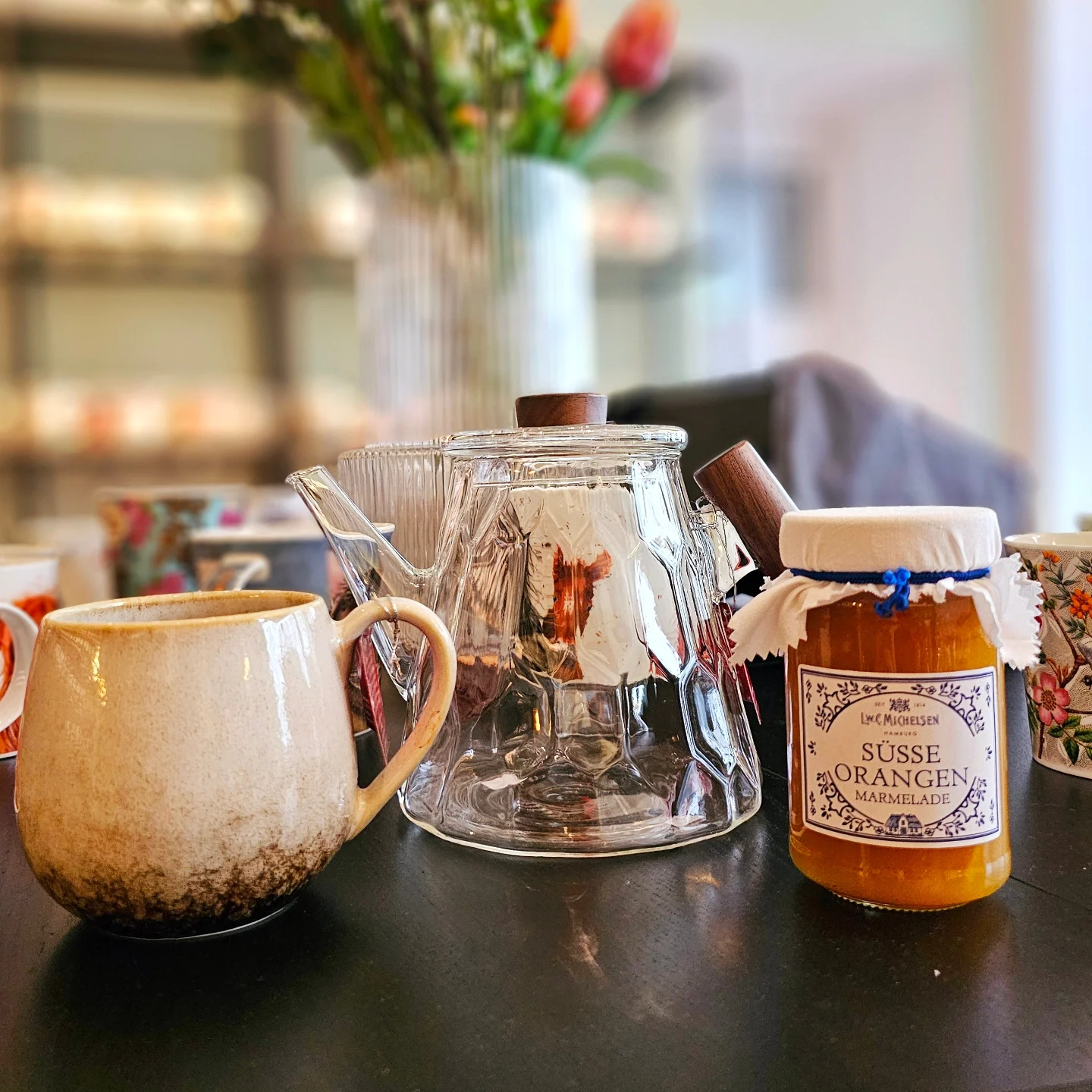 Glaskanne mit handgemachter Keramiktasse und hausgemachter Marmelade auf dem Lupercia-Tisch