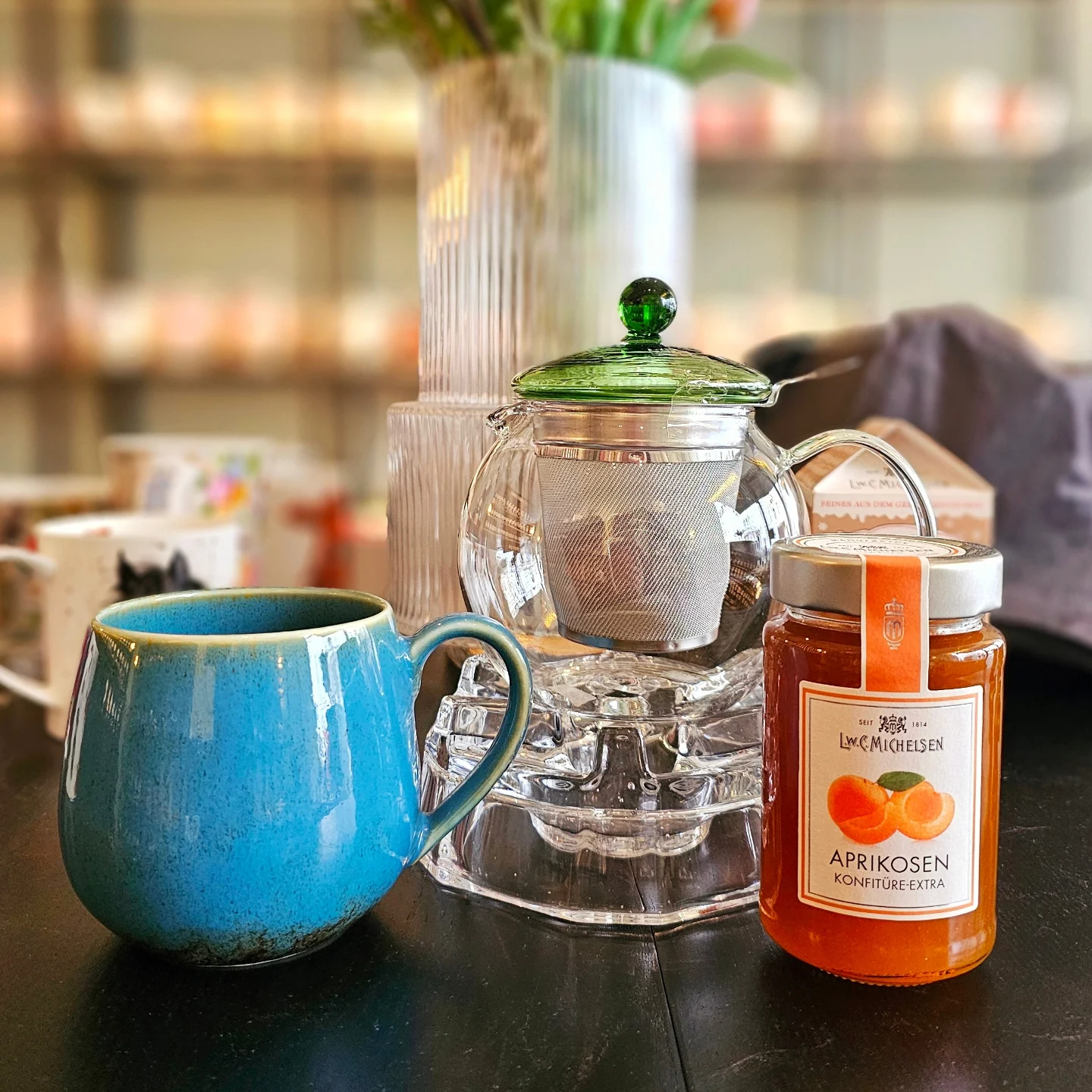 Türkise Keramiktasse mit Glaskanne im warmen Salonlicht